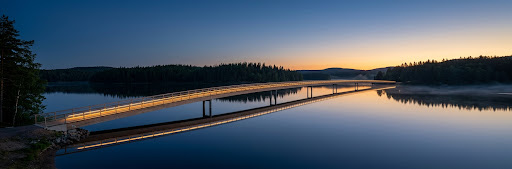 Moderne Brücke über ruhigem Wasser bei Dämmerung